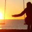Image of a woman on a swing in the sunset for a blog on bereavement support payment