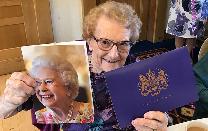 An image of Muriel Anne Rowland holding her letter from the Queen for turning 100.