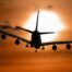 plane flying with a sunset in the background.